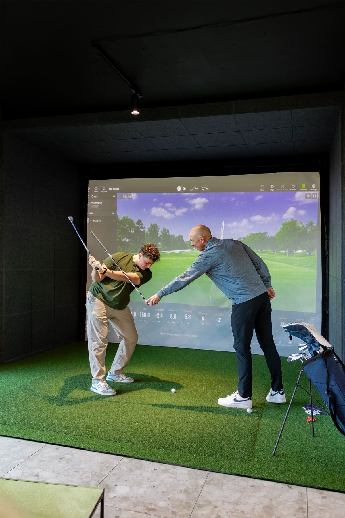 A PGA coach guiding a player through a swing in a simulator bay