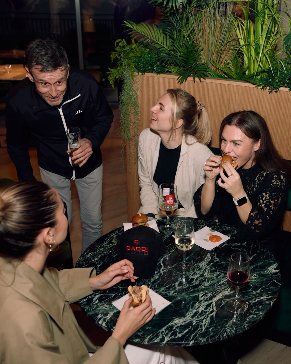 Friends sharing sliders and wine at Caddi Club
