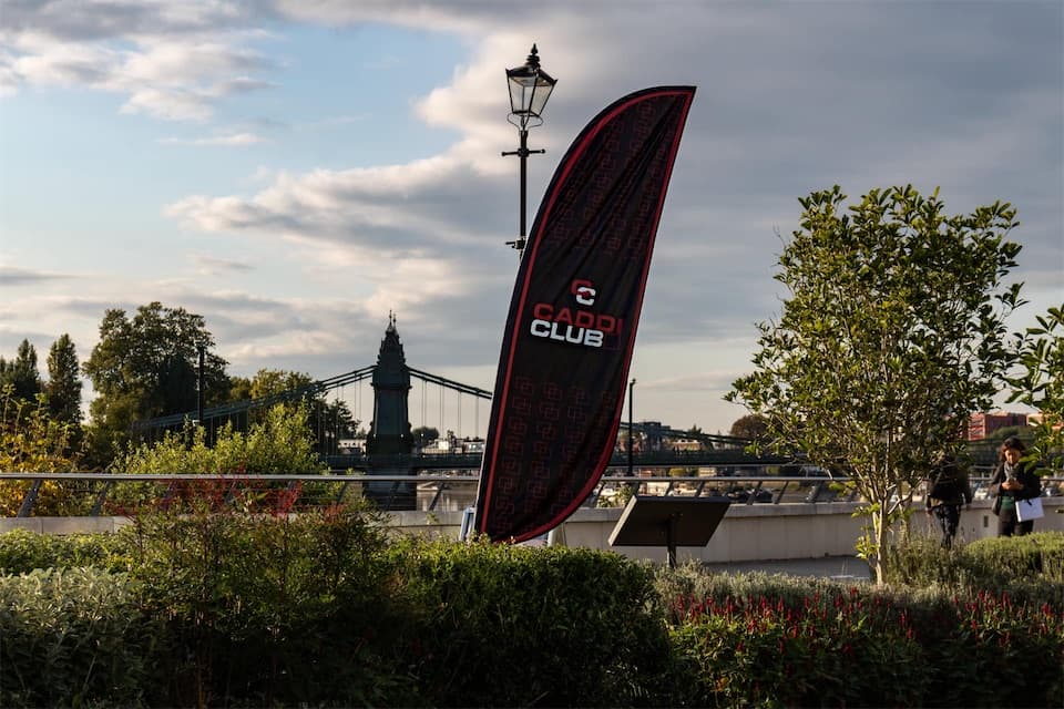 The Caddi Club flag on the Thames Path at Fulham, Hammersmith Bridge behind