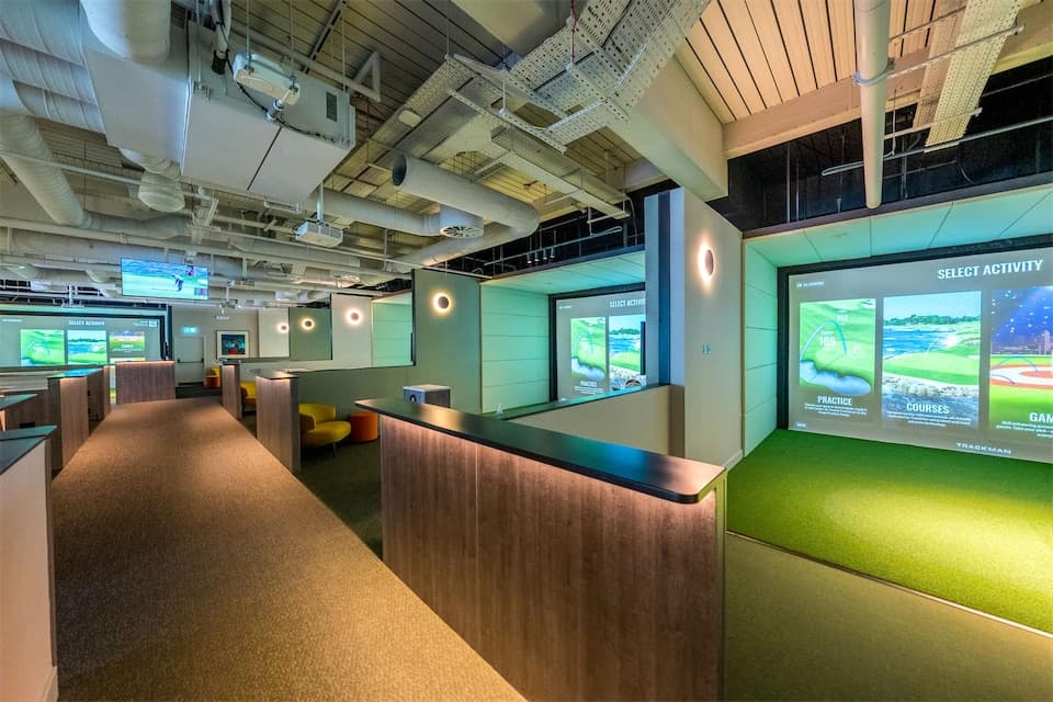 The bright corridor of simulator bays at Caddi Club Wimbledon