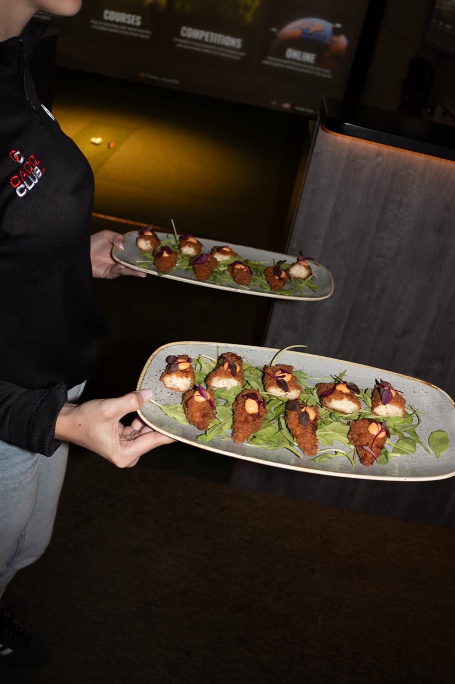 A host serving a tray of canapés at a Caddi Club party