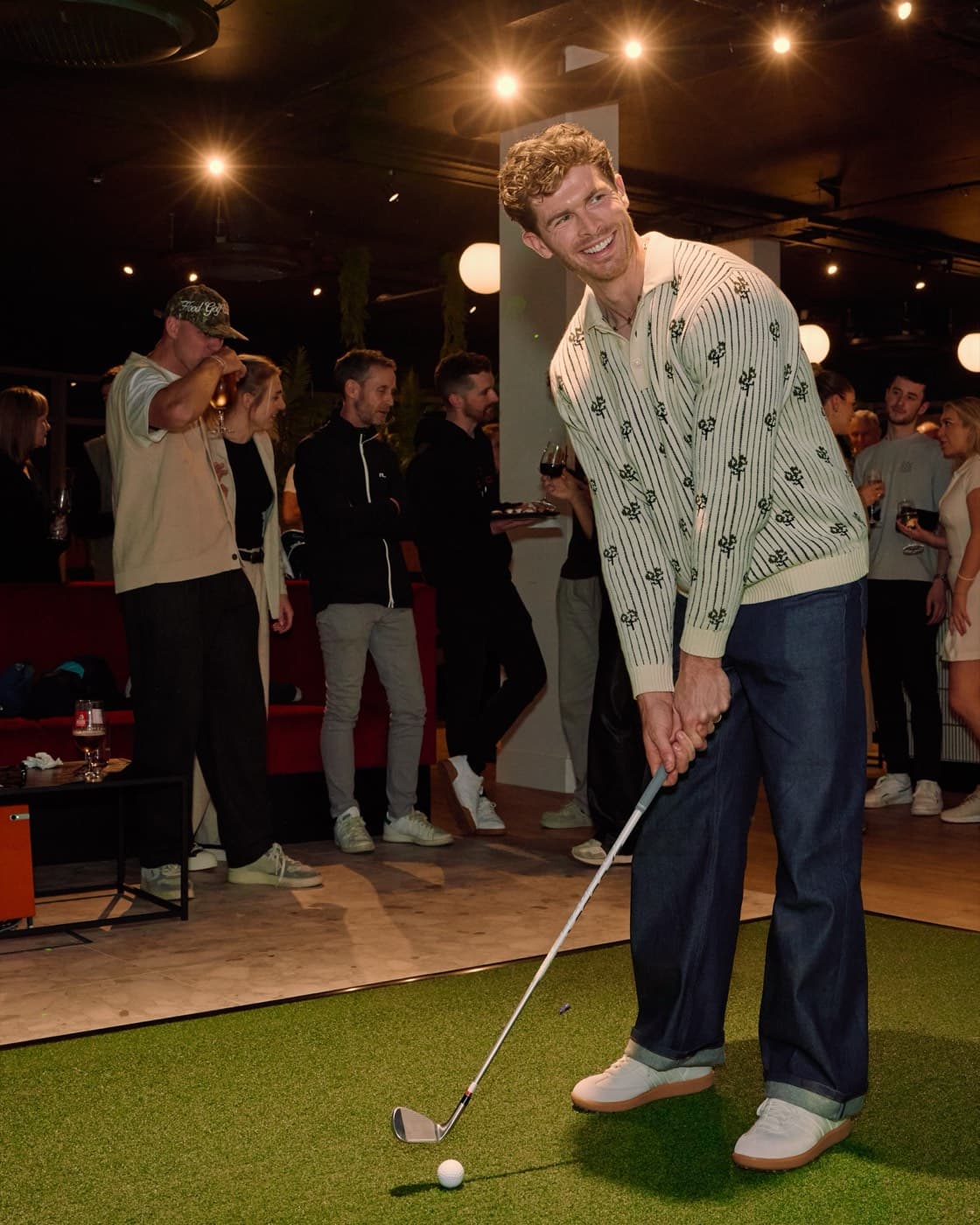A member putting while a crowd of members watches at Caddi Club
