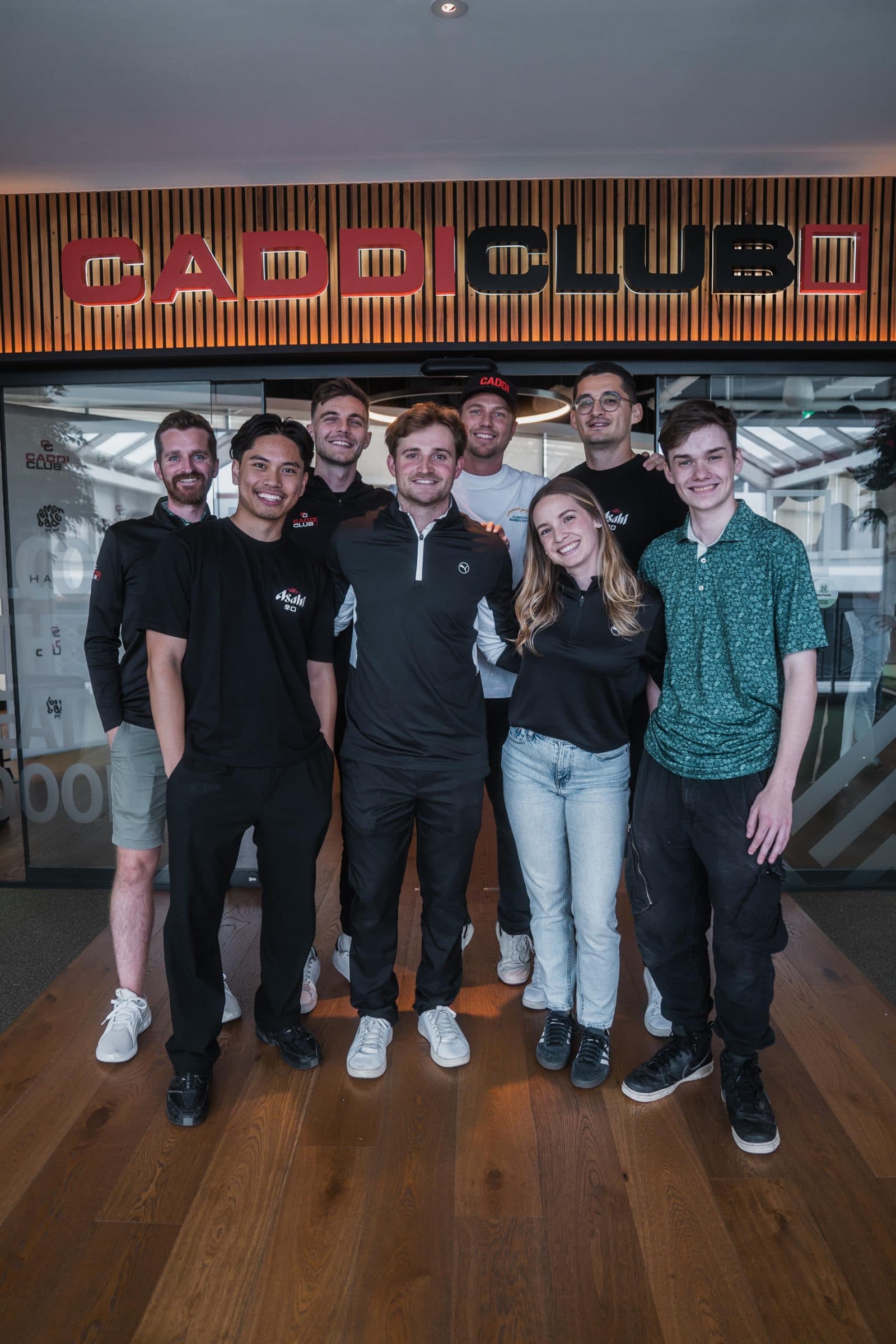 The Caddi Club team under the Caddi Club sign at our Wimbledon indoor golf venue, London